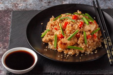 Tori chahan fried Japanese rice with vegetables and chicken in soy sauce in a black plate on a serving board