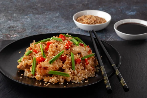 Tori chahan gebratener japanischer Reis mit Gemüse und Huhn in Sojasauce auf einem schwarzen Teller auf einem Servierbrett — Stockfoto