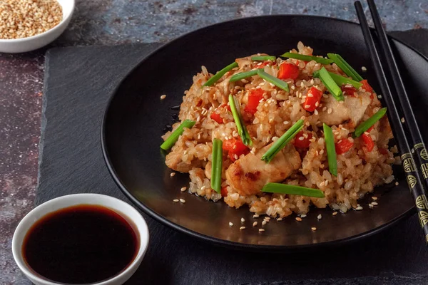 Tori chahan gebratener japanischer Reis mit Gemüse und Huhn in Sojasauce auf einem schwarzen Teller auf einem Servierbrett — Stockfoto