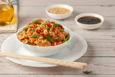 Tori chahan fried Japanese rice with vegetables and chicken in soy sauce in a black plate on a wooden table