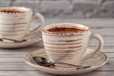 Eski beyaz ahşap bir masada iki fincan aromatik kahve..