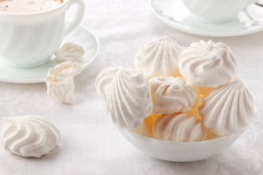 Masanın üzerinde yumuşak, havadar bir bisküvi ve kremalı bir fincan taze kahve var.