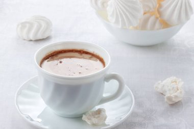 Masanın üzerinde kremalı bir fincan taze kahve ve yumuşak, havadar bir biber var.