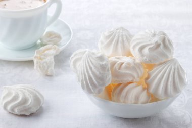 Masanın üzerinde yumuşak, havadar bir bisküvi ve kremalı bir fincan taze kahve var.