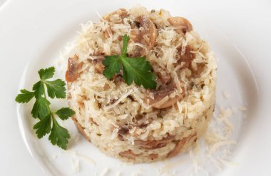 Beyaz ahşap arka planda risotto üzerine maydanozlu ve parmesanlı yabani mantarlı