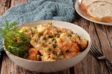 Yeşil bezelyeli tavuk fileto kaymak soslu ahşap bir masada.