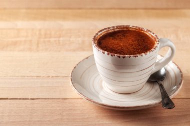 Tahta bir masanın üzerinde bir fincan taze aromatik kahve var.