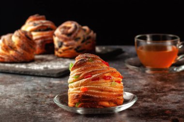 Masanın üzerinde kraffinler, şekerli meyveler ve haşhaş tohumları var, üzerine toz şeker serpiştirilmiş..