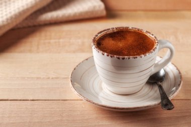 Tahta bir masanın üzerinde bir fincan taze aromatik kahve var.