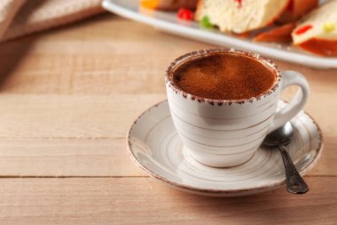 Tahta bir masanın üzerinde ev yapımı keklerle birlikte bir fincan kahve.