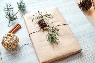 Bir kitap ya da dizüstü bilgisayar için hediye paketi sicim ipiyle bağlanmış ve bir köknar dalıyla süslenmiş.