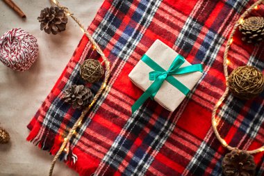 Kırmızı yün kareli bir ekose üzerinde Noel hediyeleri koni ve köknar dalları ile
