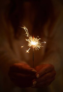 Sıcak yün kazaklı kadın maytap tutuyor, elleri yakın, romantik görünüşlü, arka plan olarak kullanıyor.