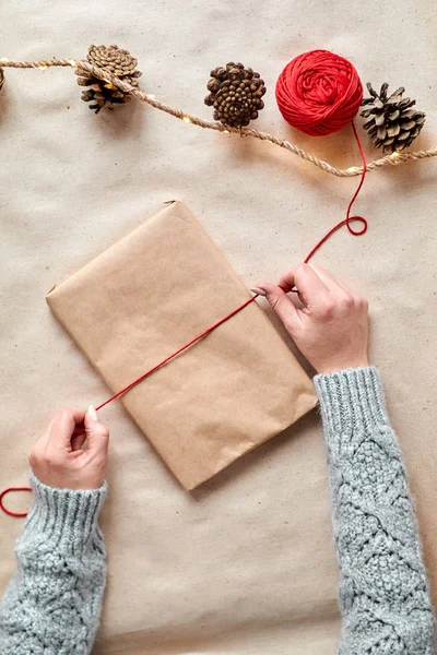 女の子は贈り物として本をパックし クラフト紙に包んで 赤いツインロープで包帯します — ストック写真