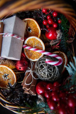 Noel sepeti çizgili şeker kamışları, dilimlenmiş portakallar, koniler ve hediyeler.