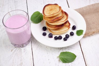 Naneli, açık ahşap arka planda yaban mersinli ve yaban mersinli yoğurtlu leziz krepler. Sağlıklı beslenme ve harika bir kahvaltı konsepti.