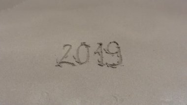 2019 'da kumsalda ıslak kumda yazılmış. Dalga yazıtlara yaklaşıyor, ama onu yıkamıyor. 2020 'ye yaklaşma konsepti. Tropik plajdaki yazıt..