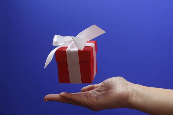 Κόκκινο κουτί δώρου με λευκό τόξο σε μπλε φόντο. — Φωτογραφία Αρχείου