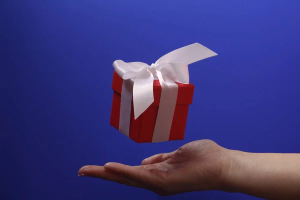 Κόκκινο κουτί δώρου με λευκό τόξο σε μπλε φόντο. — Φωτογραφία Αρχείου