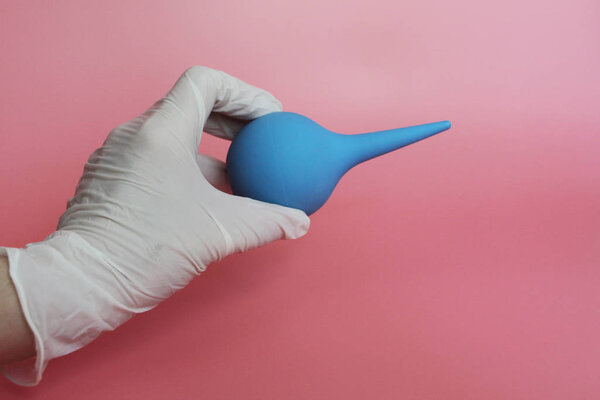 Blue syringe with a soft tip in the female hand of a doctor.