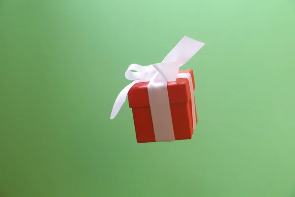 Κόκκινο κουτί δώρου με λευκό φιόγκο σε πράσινο φόντο. — Φωτογραφία Αρχείου
