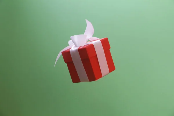 Κόκκινο κουτί δώρου με λευκό φιόγκο σε πράσινο φόντο. — Φωτογραφία Αρχείου