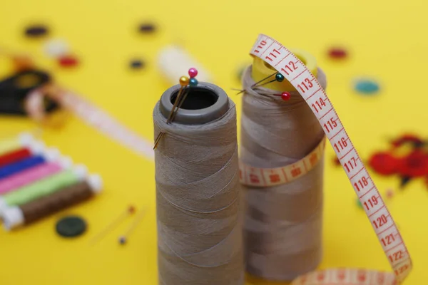 Sewing buttons and threads on a yellow background.