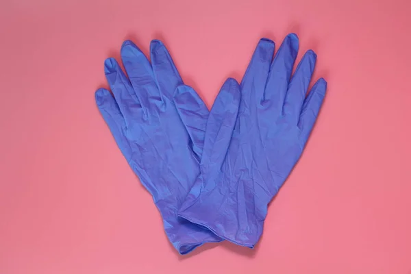 Dos guantes médicos azules sobre fondo rosa . — Foto de Stock