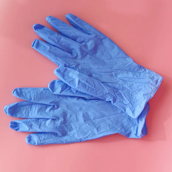 Две синие медицинские перчатки на розовом фоне . — стоковое фото
