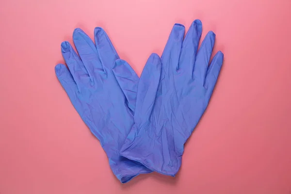 Dos guantes médicos azules sobre fondo rosa . — Foto de Stock