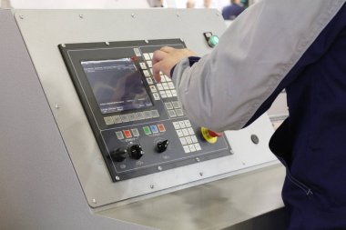 Fabrikadaki makinenin kontrol panelinde çalışan bir adamın eli..