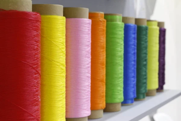 Large tubes with colored threads. Sewing production.