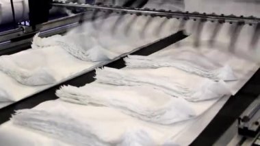Video, plastik poşet üreten bir fabrikayı gösteriyor. Şaftlar dönüyor. Selofan şaftlar arasında hareket ediyor. Polietilen poşet üretimi için kullanılan bir makinenin parçaları.