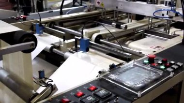 Video, plastik poşet üreten bir fabrikayı gösteriyor. Şaftlar dönüyor. Selofan şaftlar arasında hareket ediyor. Polietilen poşet üretimi için kullanılan bir makinenin parçaları.
