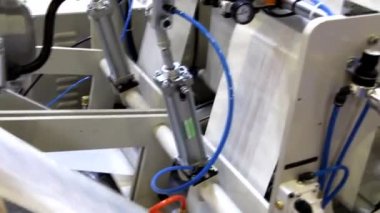 Video, plastik poşet üreten bir fabrikayı gösteriyor. Şaftlar dönüyor. Selofan şaftlar arasında hareket ediyor. Polietilen poşet üretimi için kullanılan bir makinenin parçaları.