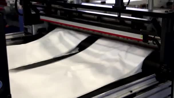 ビデオはビニール袋を製造する工場を示しています シャフトが回転してるセロファンはシャフト間を移動します ポリエチレン袋の製造用機械の断片 — ストック動画