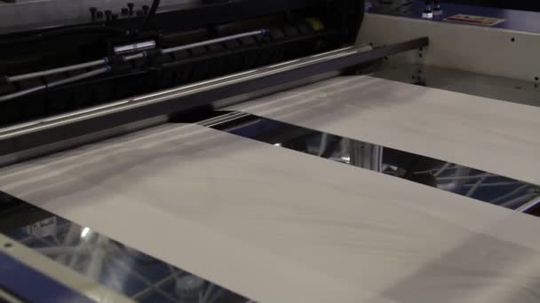 La vidéo montre une usine produisant des sacs en plastique. Les arbres tournent. Cellophane se déplace entre les arbres. Fragments d'une machine pour la production de sacs en polyéthylène .