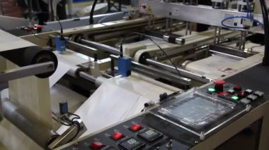 Video, plastik poşet üreten bir fabrikayı gösteriyor. Şaftlar dönüyor. Selofan şaftlar arasında hareket ediyor. Polietilen poşet üretimi için kullanılan bir makinenin parçaları.