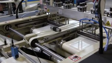 Video, plastik poşet üreten bir fabrikayı gösteriyor. Şaftlar dönüyor. Selofan şaftlar arasında hareket ediyor. Polietilen poşet üretimi için kullanılan bir makinenin parçaları.
