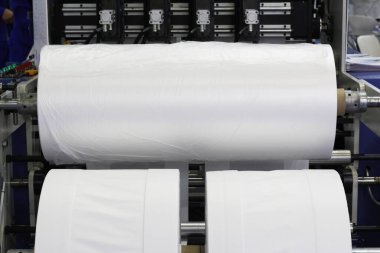 Plastik poşet üretimi için kullanılan bir makine parçası. Fabrikadaki plastik poşet üretimi. Şaftlar dönüyor. Selofan şaftlar arasında hareket eder.