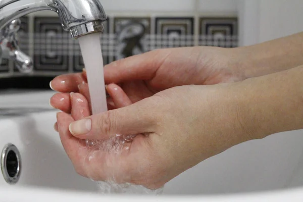 Hand washing. Wash hands under running water. Hygiene concept and virus prevention. Close up of female hands. Hand washing in the bathroom. COVID-19. Coronavirus. Coronavirus infection.