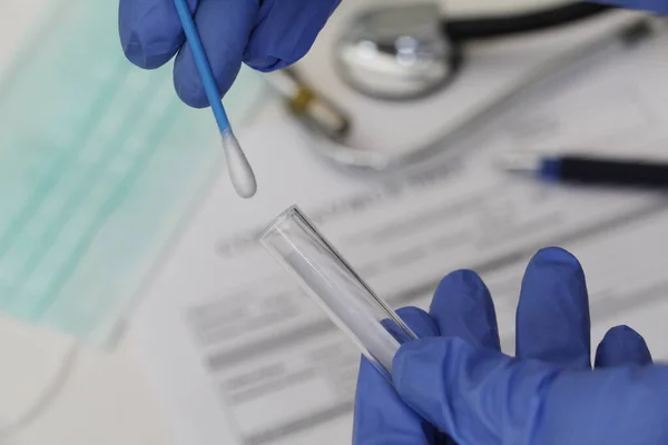 Orofarinks 'ten örnek alıyorum. Kavramsal fotoğrafçılık, koronavirüs testi. Elinde hastanın numunesinin olduğu bir test tüpü var. Coronavirus COVID-19 testi yapıldı..