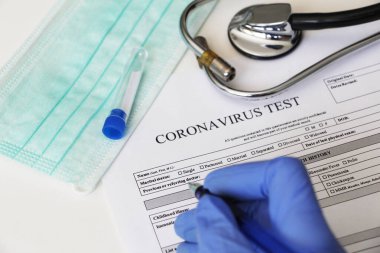 Coronavirus 'un belirlenmesi için laboratuvar testi. Kavram. Hasta analiz için onay formu dolduruyor. Masanın üzerinde testler için rıza yatıyor. Coronavirus laboratuvar testi.