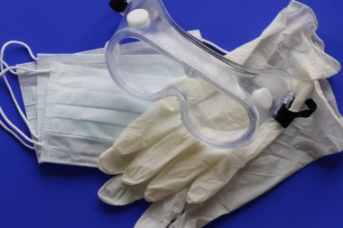 COVID-19. Coronavirus enfeksiyonu. Tek kullanımlık birkaç maske, göz koruması ve bir çift lateks eldiven. Gereken tek kullanımlık tıbbi malzemeler. Yüzün ve ellerin tıbbi koruması.