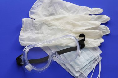 COVID-19. Coronavirus enfeksiyonu. Tek kullanımlık birkaç maske, göz koruması ve bir çift lateks eldiven. Gereken tek kullanımlık tıbbi malzemeler. Yüzün ve ellerin tıbbi koruması.