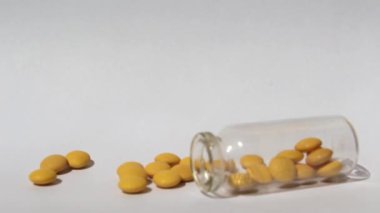 Sarı haplar cam şişeden dökülüyor. Tıp ve sağlık kavramı. Test tüpünden tabletler dökülüyor..