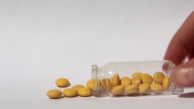 Sarı haplar cam şişeden dökülüyor. Tıp ve sağlık kavramı. Test tüpünden tabletler dökülüyor..