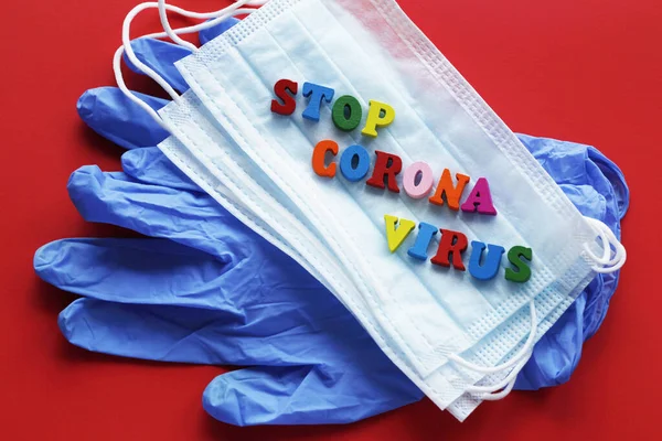 Stop Coronavirusという言葉が書かれています 赤い背景には手用のラテックス手袋と2つの医療用マスクがあります — ストック写真