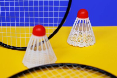 Badminton 'da. Üç mekik horozu ve iki badminton raketi. Renkli sarı arka plan. Bir dergi fikri. Sağlıklı yaşam tarzı kavramı.