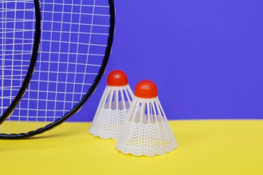 Badminton 'da. Üç mekik horozu ve iki badminton raketi. Renkli sarı arka plan. Bir dergi fikri. Sağlıklı yaşam tarzı kavramı.